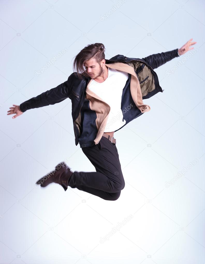 side view of a young fashion man in leather jacket jumping