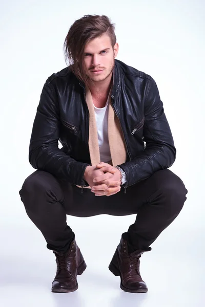 Smiling young man in leather jacket standing crouched — Stock Photo, Image