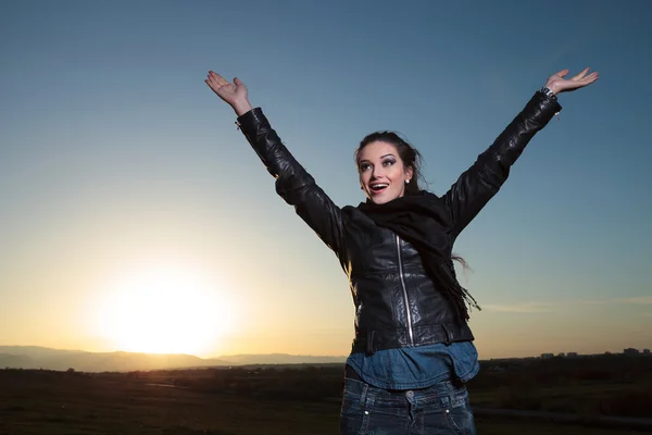 Glad kvinna med handen i luften firar i gryningen — Stockfoto