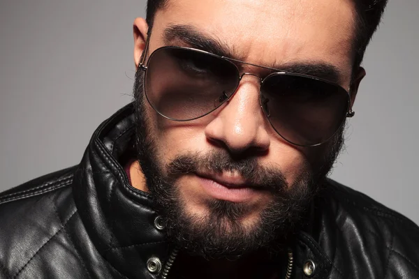 closeup picture of a young man with long beard wearing sunglasse