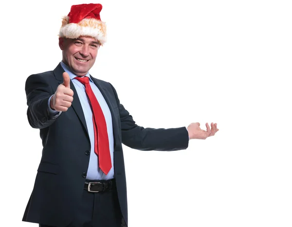 Uomo d'affari in cappello di Babbo Natale che presenta e fa il segno ok — Foto Stock