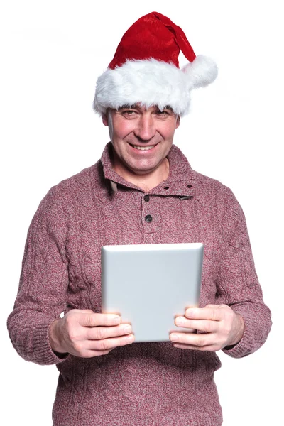 Mayor hombre casual con sombrero de santa está sosteniendo una tableta de almohadilla —  Fotos de Stock