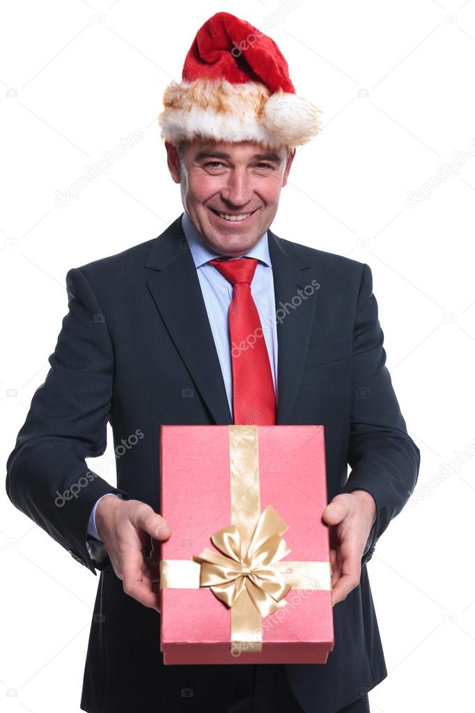 happy mature business man with santa hat is giving you a presen