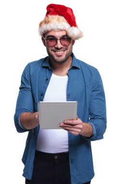 genç adam Noel Baba şapkası giyen bir tablet üzerinde çalışan