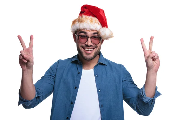 Mann mit Weihnachtsmannhut macht das Siegeszeichen — Stockfoto