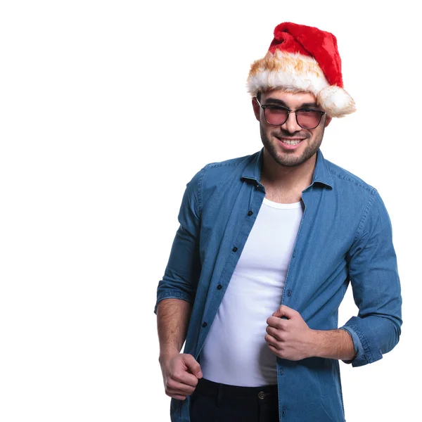 Sorrindo homem em santa chapéu está puxando sua camisa — Fotografia de Stock