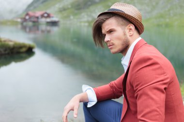 Kabin bir göl kenarında oturan dalgın moda adam