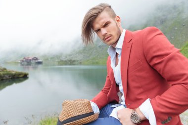 Casual fashion adam bir göl kenarında oturuyor