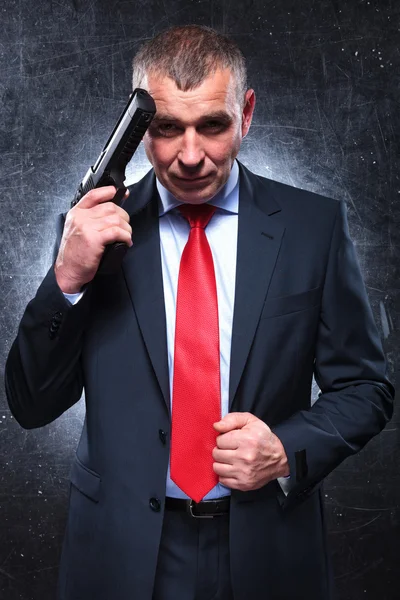 Smiling old killer holding his gun and pulling his suit — Stock Photo, Image