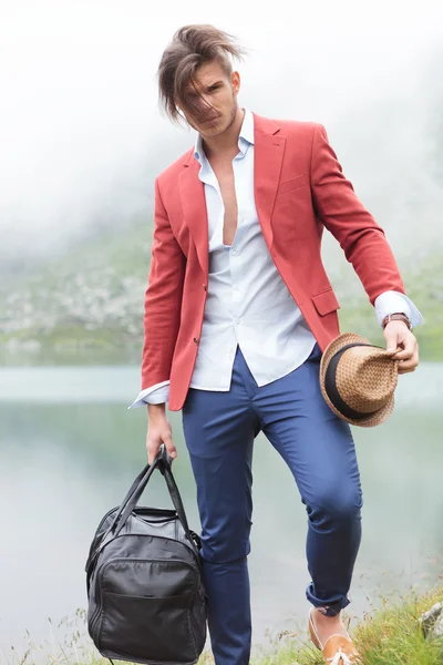 Hombre con el pelo soplado está de pie frente a un lago — Foto de Stock