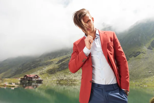 Uomo tirando i capelli di fronte a un lago di montagna — Foto Stock