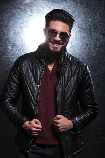 Man pulling on his leather jacket and smiles — Stock Photo, Image