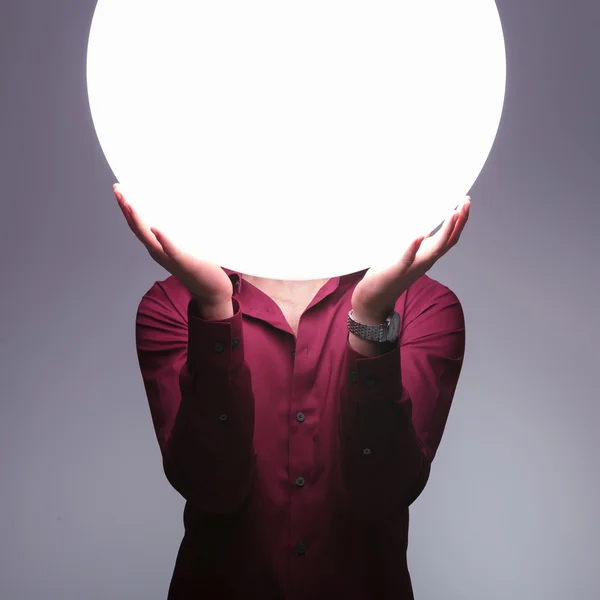 Homem está segurando grande esfera de luz sobre seu rosto — Fotografia de Stock