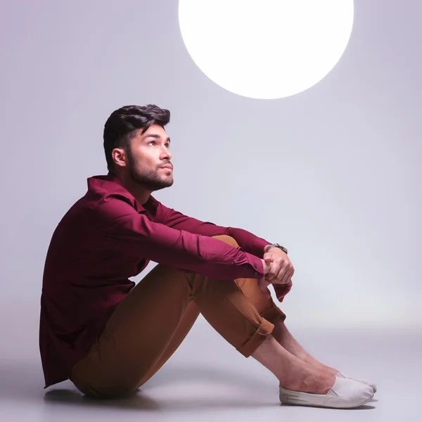 Seated casual man looking at a ball of light — стоковое фото