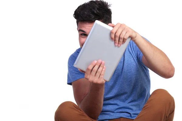 Schüchterner, lässiger Mann blickt hinter sein Tablet-Pad — Stockfoto
