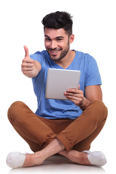 Seated happy man reading good news on his tablet