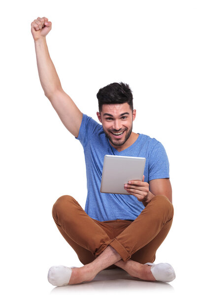 seated man with tablet pad celebrating success