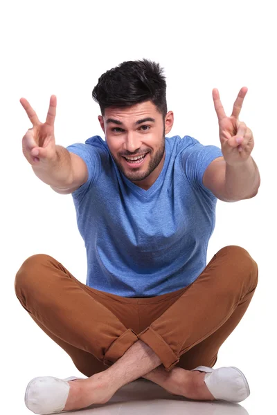 Happy seated casual man making the victory sign — Stock Photo, Image
