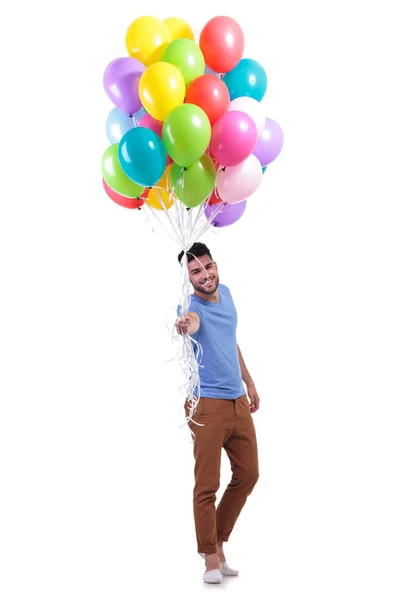 Sorrindo homem casual está oferecendo um monte de balões — Fotografia de Stock