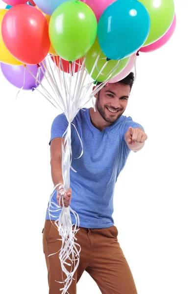 Man holding balloons and pointing to the camera — Stock Photo, Image
