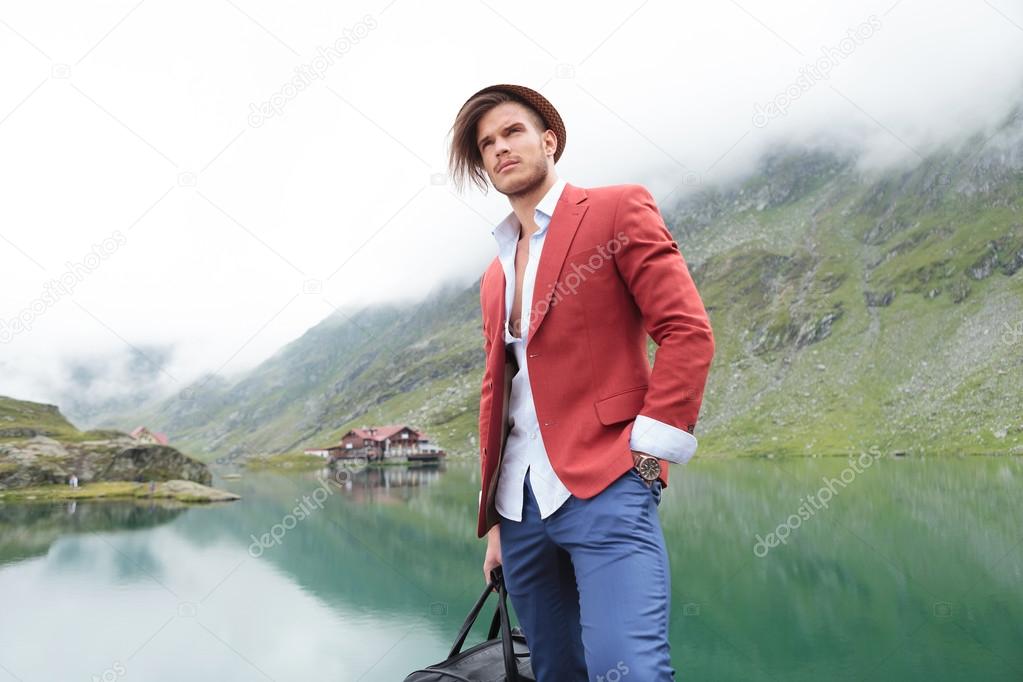 young traveler near mountain lake with cabin