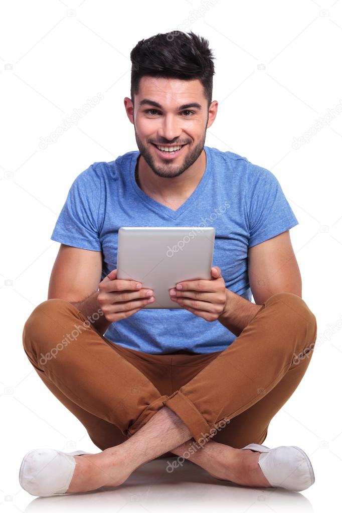 seated young man with tablet pad smiling
