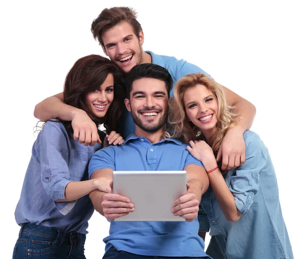 Quatro risos pessoas casuais lendo em um tablet pad computador — Fotografia de Stock