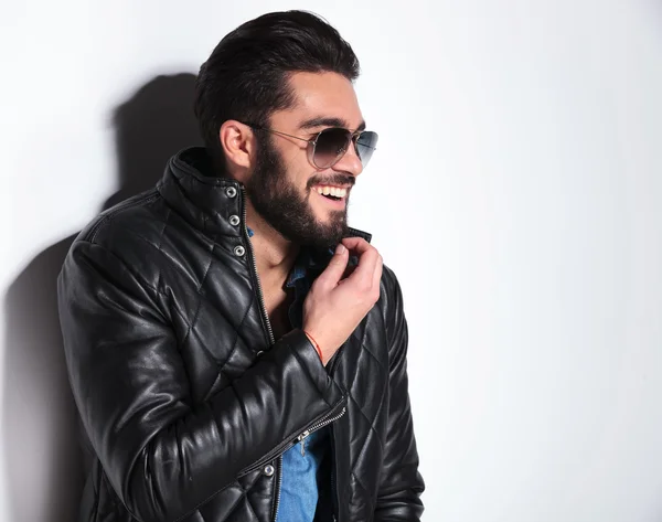 Laughing man in leather jacket pulling his beard — Stock Photo, Image