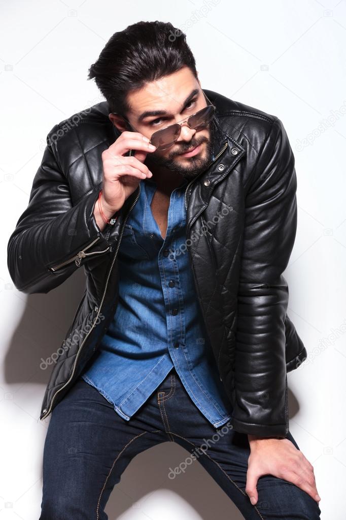 Young man in leather jacket taking off his sunglasses