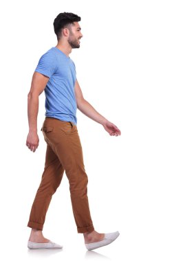 side view of a casual man walking forward and smiling