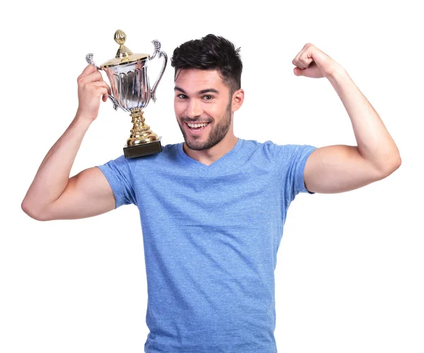 Hombre flexionando su músculo y sosteniendo una copa de trofeo — Foto de Stock