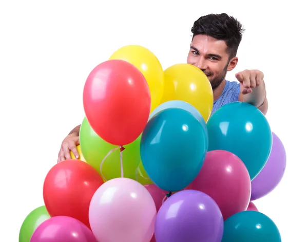 Lässiger Mann hinter Luftballons zeigt mit Finger — Stockfoto