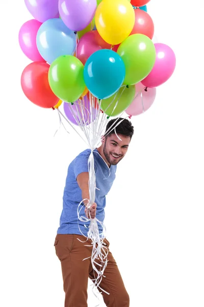 Happy casual man giving away a bunch of baloons — Stock Photo, Image