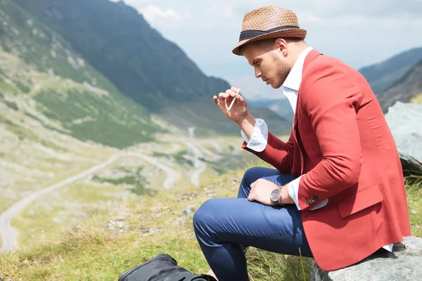 Young fashion man smokes in nature — Stock Photo, Image