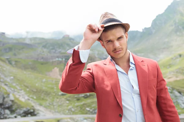 Outdoor fashion man holds his hand on his hat — Stock Photo, Image