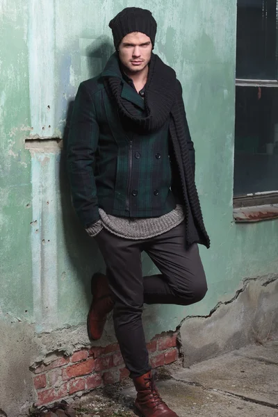 Junger Modemann hält Fuß auf alte Mauer — Stockfoto