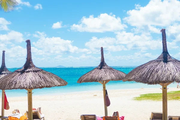 Şezlonglar ve şemsiyeler saman ile güzel bir plaj — Stok fotoğraf