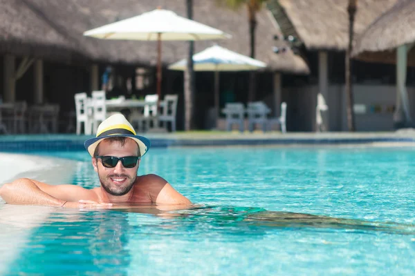 Man wearing hat and sunglasses relaxing at the pool — Stock Photo, Image