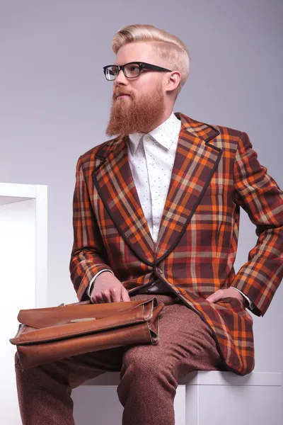 Lado de un modelo masculino de moda sentado sosteniendo su maletín — Foto de Stock