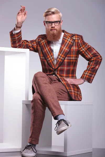 Fashion man with long beard is sitting and smoking — Stock Photo, Image