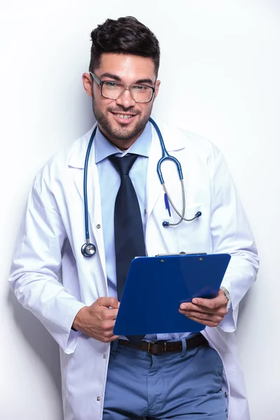 Young doctor smiles with clipboard in hand — Stock Photo, Image