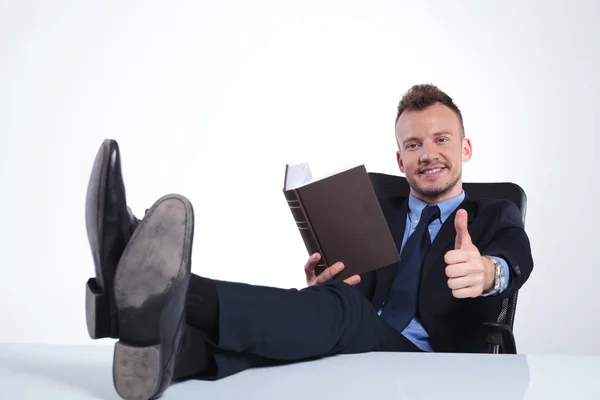 Geschäftsmann liest mit Füßen auf Schreibtisch — Stockfoto