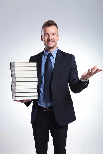 Zakenman verwelkomt u met boeken — Stockfoto