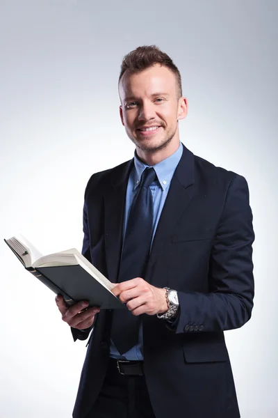 Business man smiles with book in hand — Stock Photo, Image