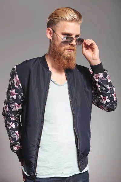 Bearded young man looks over glasses — Stock Photo, Image