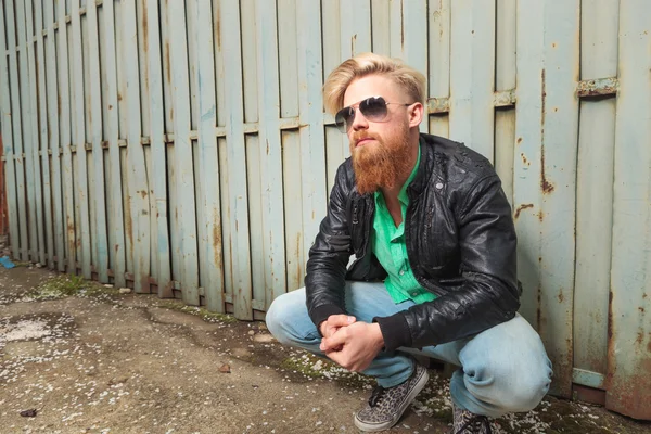 Crouched young bearded man — Stock Photo, Image