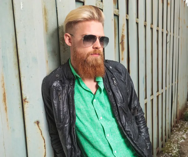 Young bearded man leans on iron fence — Stock Photo, Image