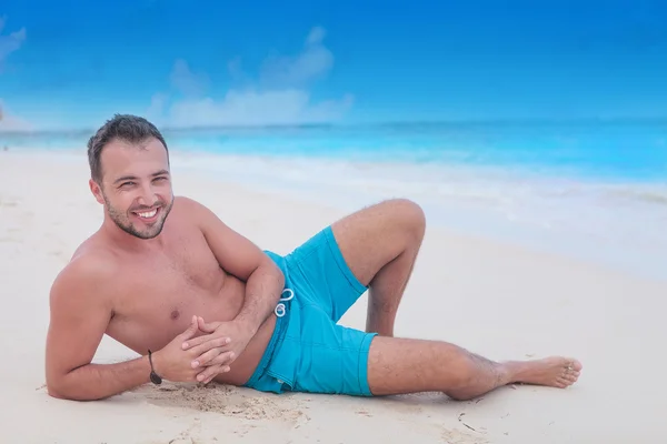 Glücklicher junger Mann ruht sich am Strand aus — Stockfoto
