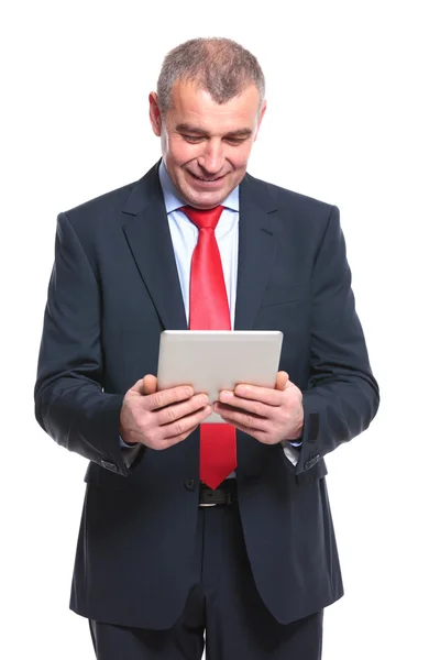 Homem de negócios olha para o seu tablet — Fotografia de Stock