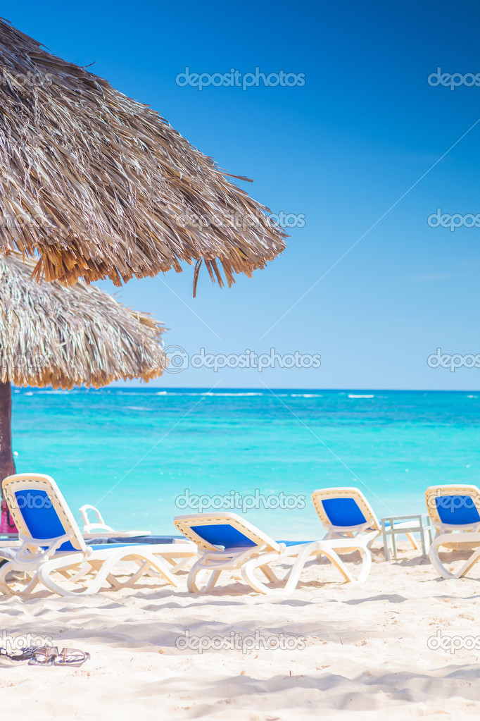 chairs and straw umbrellas on stunning tropical beach